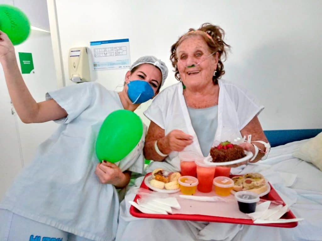 Paciente Flora Teodoro comemorando seus 82 anos com equipe do Hutrin em acolhimento musical. Foto: Divulgação.